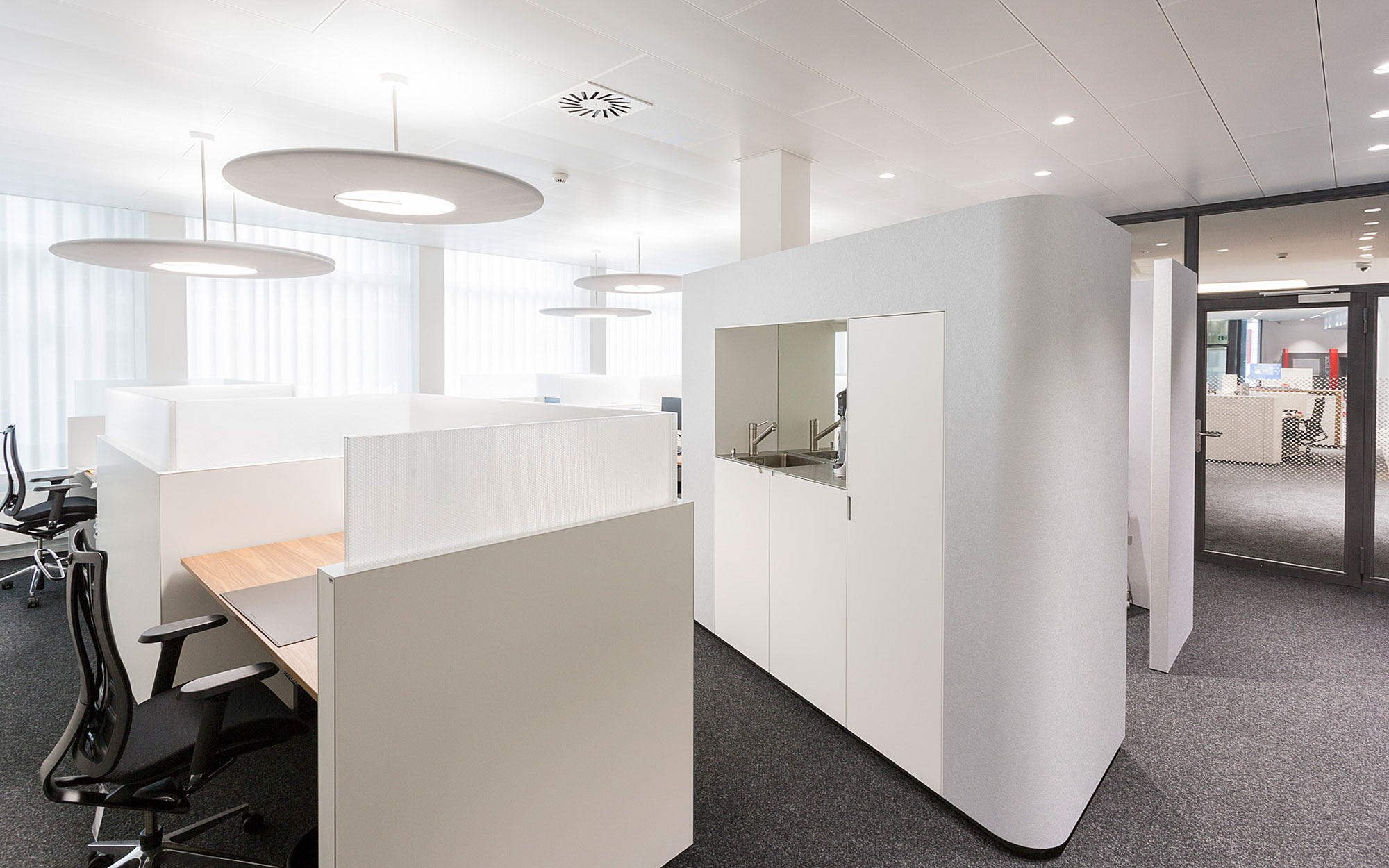 Weisse Möbel im Teamoffice nehmen die abgerundete Formstruktur wieder auf.