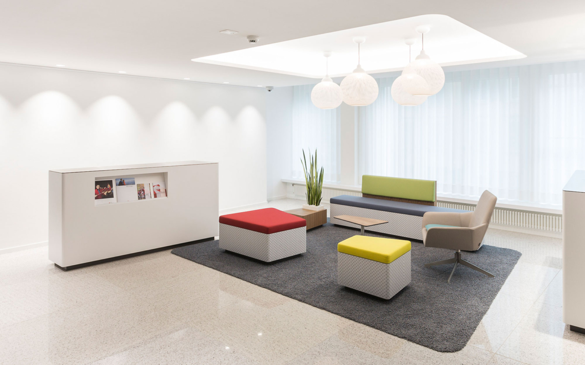 Wartezone für Kunden mit farbigen, rechteckigen Hockern